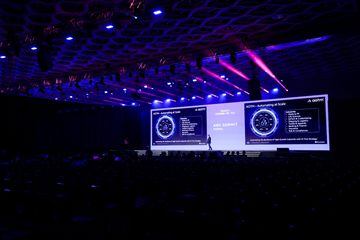 &lsquo;AOTM &mdash; Automating at Scale&rsquo; slide on stage at AWS Summit Mumbai 2025.